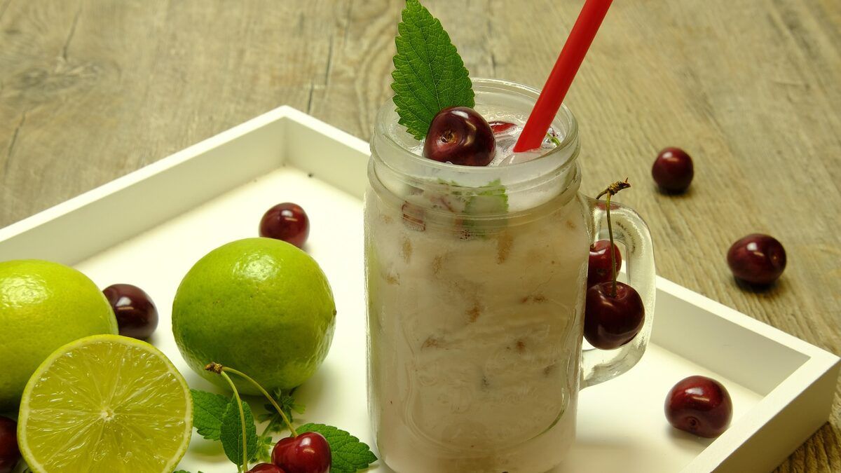 A chilled drink with lime and cherries on a tray
