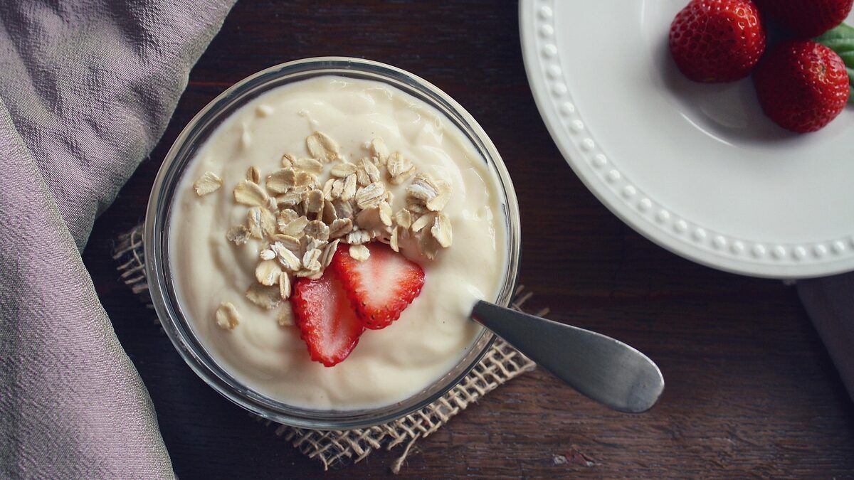 A bowl of yoghurt topped with oats and strawberries